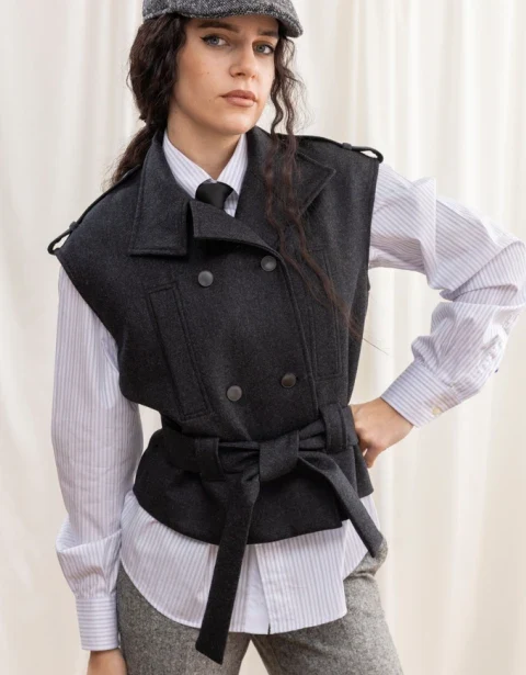 Model in a black belted wool vest over a striped shirt